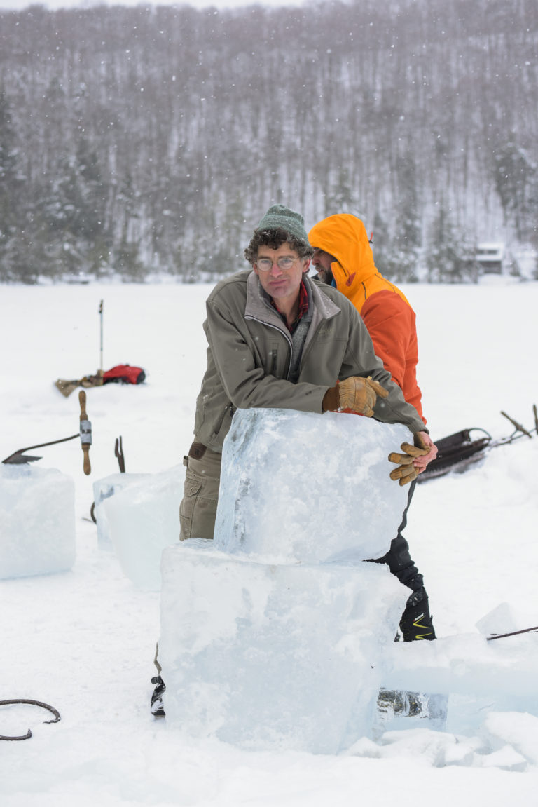 man holding large blocks of ice outside