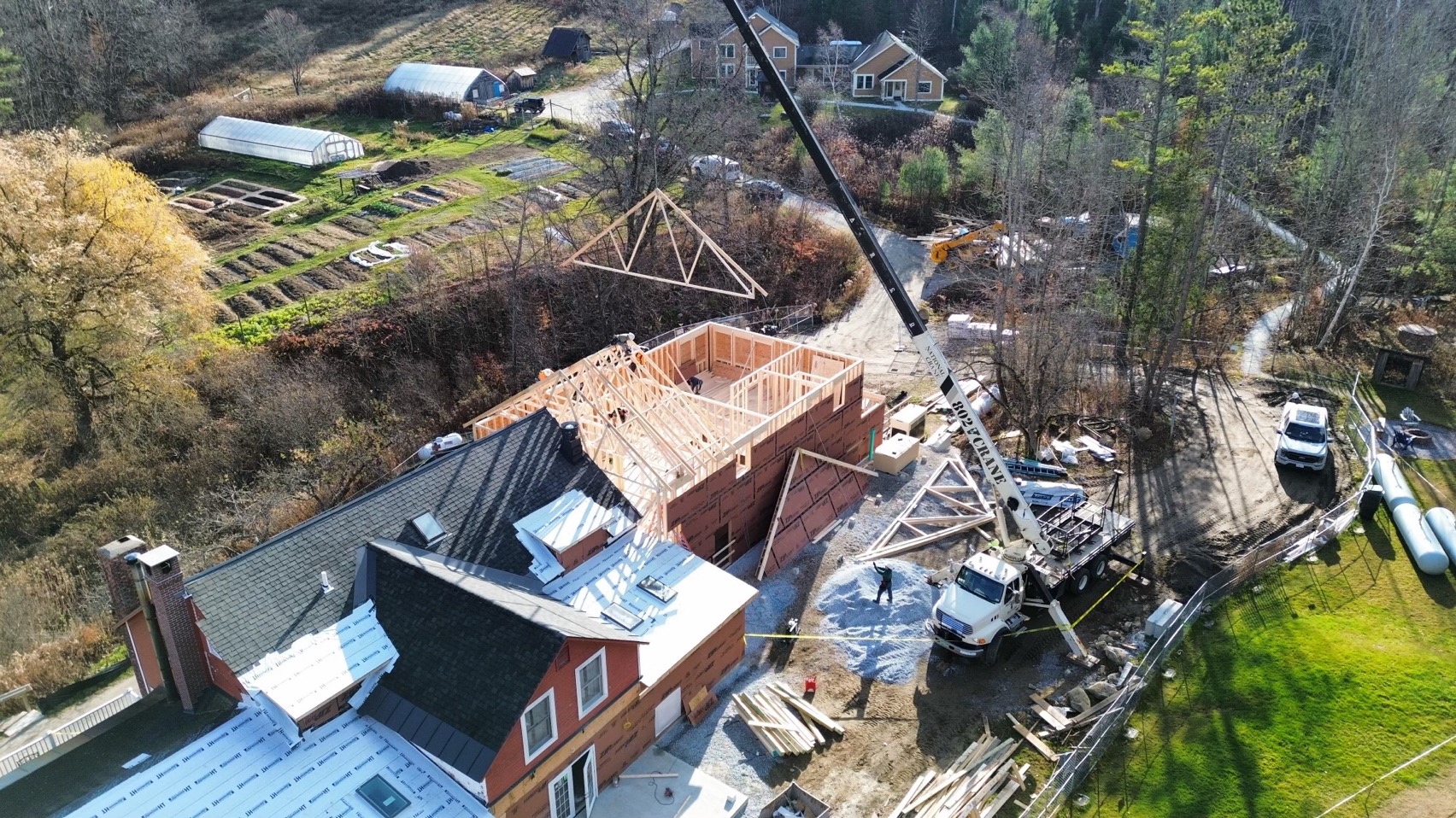 Drone shot of construction on Spring Lake Ranch Main House includes a crane lifting a roof frame onto the top of the building